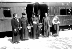 Sacerdotes despidiendo a un obispo, frente a formación ferroviaria