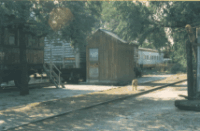 Casilla de madera y vagones habitados, frente a la estación